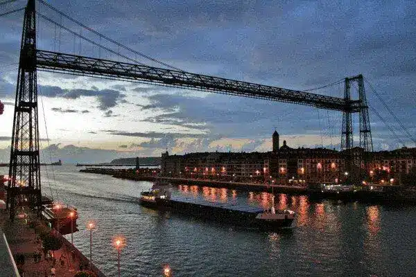 Puente con barco atravesando por debajo de noche